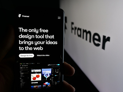 In this photo illustration, a person is holding a cellphone with the webpage of Dutch design platform company Framer B.V. on screen in front of logo.