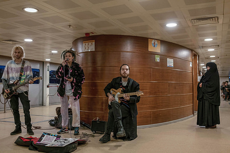 A woman in a black chador looks at the band singing on the Karakoy-Kadikoy ferry.