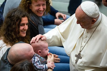Pope Francis blesses a baby among faithful devotees during his traditional Wednesday General Audience in Paul VI Audience Hall in Vatican City.