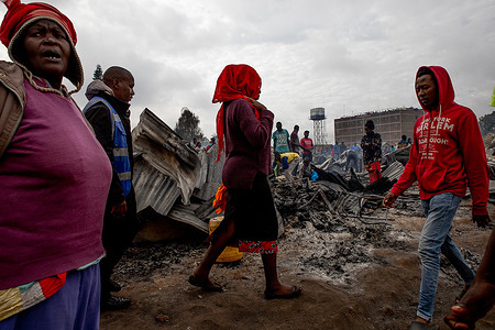 Traders desperately walk by the remains of their burnt properties from the ashes of a fire that razed down business and stalls in Kibera's Toi Market in Nairobi. Local traders at Toi Market in Kibera Slum are faced with a huge loss after a fire razed their businesses and stalls. The traders lost their goods worth millions of Kenyan shillings. Traders said they were unsure about the cause of the fire as it started at dawn.
