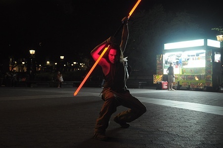 A person holds a toy lightsaber from the film franchise, "Star Wars," in Washington Square Park, Manhattan, New York City.