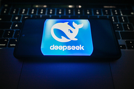 In this photo illustration, a DeepSeek logo is seen displayed on a smartphone on the top of a laptop.