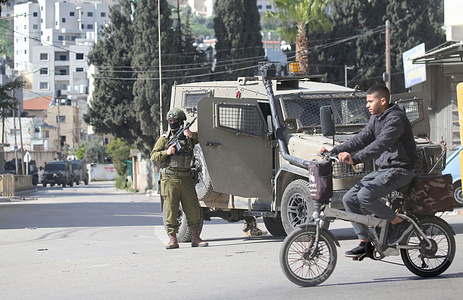 A Palestinian man rides past an Israeli military vehicle guarding religious Jews who entered Joseph's Tomb. Dozens of religious Jews illegally entered the site which is under Palestinian security control. Israeli forces then entered the area to secure their exit.