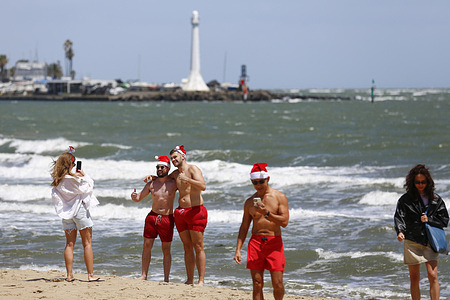 Families and friends enjoy the windy conditions at St Kilda Beach. Melbourne experiences cold and windy conditions on Christmas Day, particularly along the coast, as beachgoers at St Kilda Beach brave gusty weather. Weather conditions vary across Australia, with other major cities experiencing a mix of heat, showers, and milder summer temperatures as the country marks the holiday.