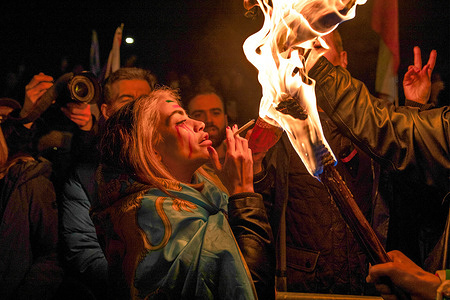 An activist lights a cigarette from a flaming torch during a protest outside the Iranian Embassy. In response to widespread civil unrest in Iran and governmental reprisals, activists organised a demonstration outside the Iranian Embassy in London. The event, coordinated by several groups opposed to the theocratic regime, drew crowds to the Kensington location in support of protestors in Iran.