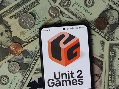 In this photo illustration, a Unit 2 Games Limited logo seen displayed on a smartphone with United States Dollar notes and coins in the background.