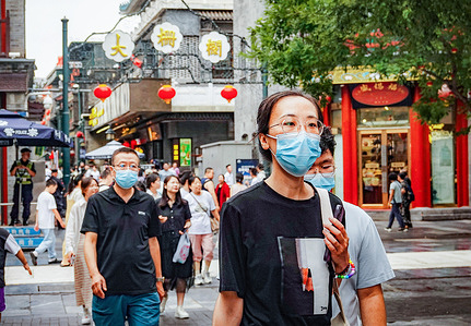 Some tourists walk on Qianmen Street in Beijing. Qianmen Street is a very famous commercial street in Beijing. It is located on the central axis of the capital.