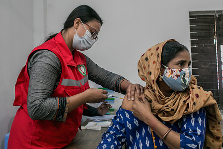 A health worker administers a dose of Oxford-AstraZeneca to a woman at a Korail slum vaccination center in Dhaka.
The government is inoculating the residents of Korail slum, one of the most densely populated low-income areas in Dhaka. The Directorate General of Health Services (DGHS) plans to provide Covid-19 vaccines to some 300,000 people living in the slum.