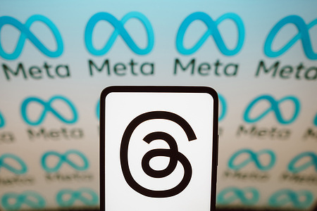In this photo illustration, the Threads logo is displayed on a smartphone screen with a Meta logo in the background. Meta has recently released its text-based platform rival to Twitter called Threads.