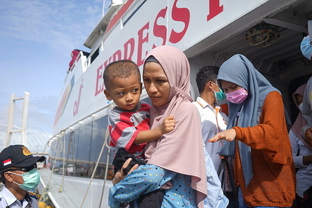 A homecoming traveler seen carrying her child off the ship.
The returning home of travelers through the sea route is dominated by people who come from Buton Island and Muna Island but live in Kendari because they work or study in Kendari.