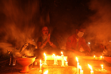 A devotee offering prayers next to lit candles during the festival.
Every year, Hindu devotees mainly the followers of Lokenath Brahmachari, mostly known as Baba Lokenath Light small lamps with special incense, fast and pray to the gods for favors at different branches of Shri Shri Lokenath Brahmachari Ashram during the traditional ritual called Rakher Upobash festival.