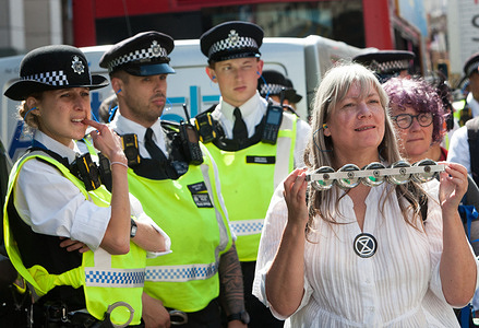 Police officers having a good look at protesters at Oxford Circus, during the Impossible Rebellion - Day 3.Led by Female, Intersex, Non-binary and Trans (FINT) people from Extinction Rebellion, rebels demand that government change policies to address the ecological and climate emergency and immediately stop all new fossil fuel investments.