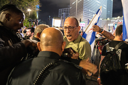 Israeli police officers push back a protester following a demonstration roadblock of the Ayalon highway. Israeli anti-judicial reform protesters block the Ayalon highway.