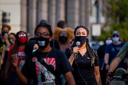 A woman leads the crowd in singing as they walk down 14th Street en route to Freedom Plaza during the Let Freedom Sing, a community-building protest and voter registration event by the Freedom Day Foundation and Head Count.