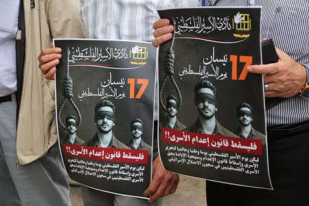 Palestinians hold placards demanding an end to the death penalty imposed on Palestinian prisoners in Israeli jails, and calling for the release of their relatives and the repeal of the death penalty law passed by the Israeli Knesset at the entrance to the commercial market in Nablus, West Bank.