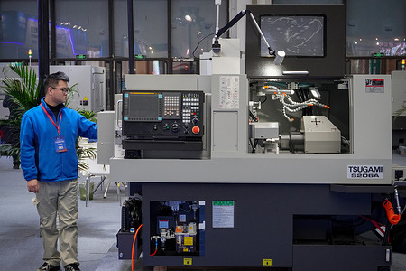 A technician stands next to a CNC lathe at the Changzhou International Industrial Equipment Expo.