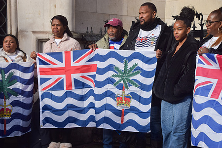 Members of the Chagossian community stand with Chagos Islands flags outside the Royal Courts of Justice during a judicial review challenging the UK government decision to hand over Chagos Islands to Mauritius.