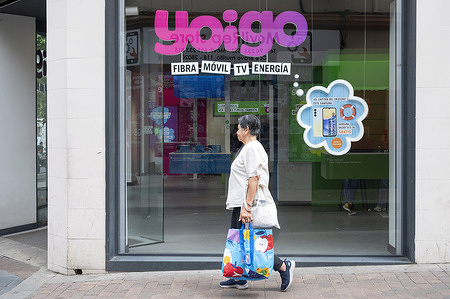 A pedestrian walks past the Spanish multinational telecommunications corporation and phone operator, Yoigo, store in Spain.
