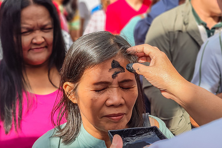A worshipper receives the imposition of ashes on their forehead during an Ash Wednesday service at the cathedral in Antipolo City, Philippines. The ash cross serves as a traditional symbol of penance and a reminder of human mortality as the global Catholic Church enters the Lenten season leading up to Holy Week and Easter Sunday.