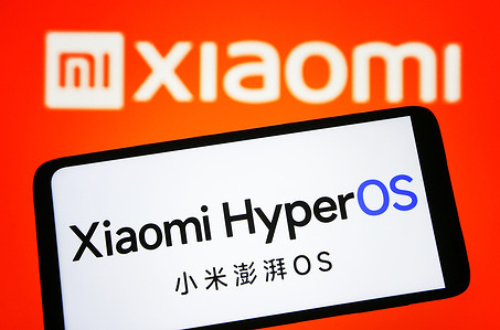 In this photo illustration, Xiaomi HyperOS logo is seen on a smartphone and Xiaomi logo in the background.