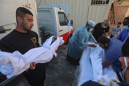 (EDITOR'S NOTE: Image depicts death) 
A Palestinian man carries the body of a child killed in Israeli strikes, at Shuhada Al-Aqsa hospital in the central Gaza Strip.