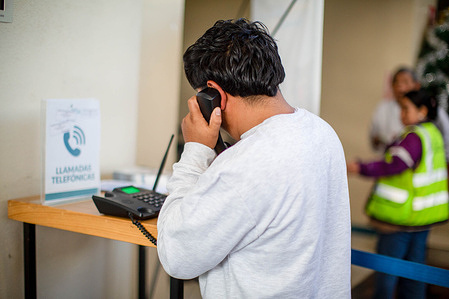 A deported Guatemalan man speaks on the phone with his family at the immigration center as a flight waits to transport deported Guatemalans from the United States to La Aurora International Airport in Guatemala City.