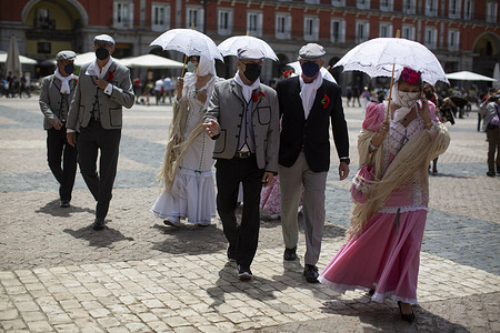 A group of friends dressed in traditional "Chulapo" and "Chulapa" costumes walk through the Plaza Mayor in Madrid during the celebrations of the day of the patron saint of Madrid, San Isidro Labrador.