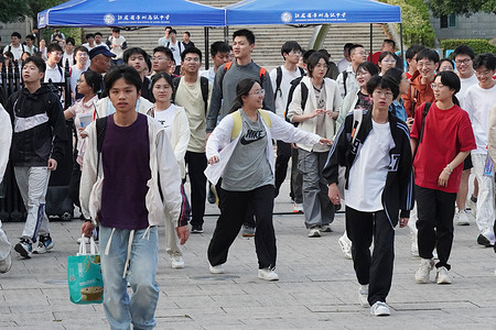 Students stream out of the exam site under blue tents marked with the school's name while exiting the 2026 National College Entrance Examination mathematics session.