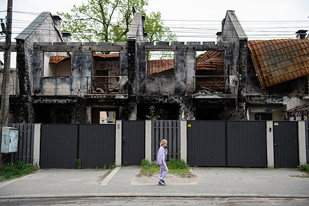 A young girl walks past a row of destroyed buildings on a newly renovated street in Irpin, Ukraine. Irpin, a suburb of Ukraine's capital city Kyiv, was the center of heavy fighting between Russian and Ukrainian forces at the outset of the Russian Invasion of Ukraine. As a result, a large portion of the city was destroyed. A year after the fighting, residents have returned, and rebuilding the city has begun which is aided by locals and volunteer groups.