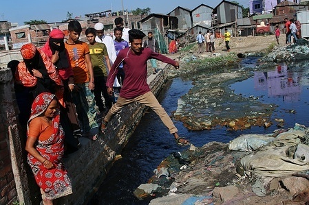 People are seen crossing a road by jumping over a wall as the road is flooded by the textile mill's wastage at Shyampur industrial area in Dhaka.
Most people in this area have become victims of pollution due to the presence of toxic chemicals, mainly dyeing chemicals. Due to the unplanned sewage system of textile mills, residents of this area suffering for a long time.