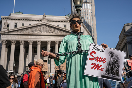 A protester in chains, dressed as the Statue Of Liberty, holds a sign that reads "Please Save Me" during a May Day rally at Foley Square in New York City. Hundreds of activists and community members gathered to recognize May Day, also known as International Workers Day, calling for workers rights, and the abolishing of ICE at Foley Square in New York City.