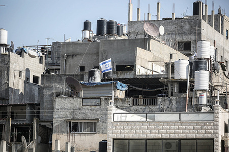 Israeli army forces raised the Israeli flag over a Palestinian building they had barricaded themselves, in the Tulkarm refugee camp, east of the city of Tulkarm, in the northern West Bank. Military bulldozers continue to demolish 165 Palestinian homes, supported by Israeli military forces, as part of a large-scale home demolitions in the camp.