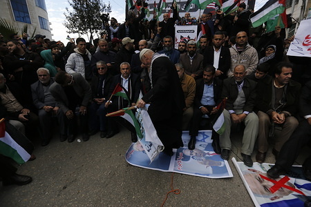 An elderly Palestinian protester steps on posters depicting US President, Donald Trump and Benjamin Netanyahu during a protest against the US peace plan about the Middle East in Rafah.