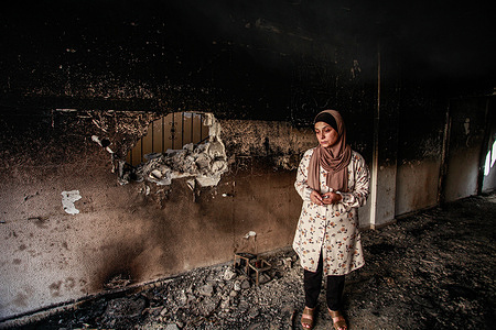A woman inspects a house damaged after an Israeli military raid in Jenin refugee camp in the West Bank.