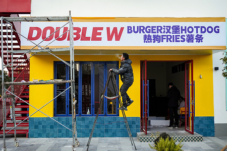 A worker paints the bright yellow exterior of the Double W burger restaurant.