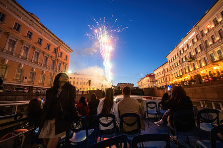 People watch the fireworks from a motor boat in Neva River on an evening summer day in St. Petersburg.