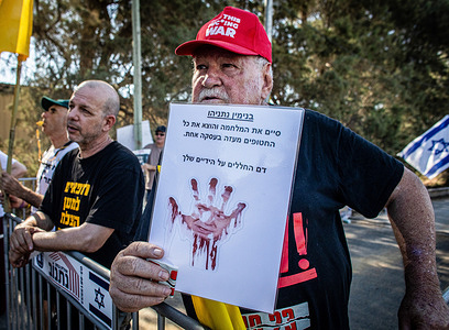 A protester holds a placard showing Israeli Prime Minister Benjamin Netanyahu at the entrance of Kibbutz Nir Oz before the visit of Netanyahu. Israeli Prime Minister Benjamin Netanyahu made his first visit to Kibbutz Nir Oz, near the Gaza border, since the October 7 massacre, nearly 21 months after the Hamas-led attack in which one in four residents were either killed or kidnapped. He was met at the entrance by a sign reading "Mr. Abandonment" and by angry survivors who accused him of seeking political redemption without acknowledging the state’s failure to protect them.