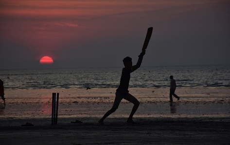 Local people seen playing cricket at Juhu Beach in Mumbai during the sunset.