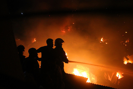 Fire-fighting units with the help of local people are seen trying to douse the fire that broke out at Mirpur slum in Dhaka.
A total of 24 units of firefighters brought the blaze under control at around 10:35pm, over three hours after it originated at the slum around 7:20pm on Friday evening and soon engulfed the shanties there, said sources at Fire Service and Civil Defence control room.
