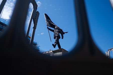 Contractors work on placing barriers around the new Banksy statue in Pall Mall. The work shows a man in a suit stepping off a plinth, blinded by the flag he is carrying which has flown and wrapped itself around his head. Banksy confirms that the work is his, and an Instagram reel has been shared in which the statue is placed in the early hours of the morning. Westminster Council has confirmed that they are in discussions of the future of the statue.