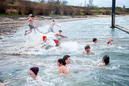 People are feeling the extreme cold water while diving. This year, the Nijmegen Student Sports Council (NSSR) organized the New Year's dive in the Spiegelwaal in Nijmegen. Families and students enjoyed the tradition during a very cold day. Participants could purchase a variety of hot refreshments after their dip in the cold water. The proceeds went to charity.