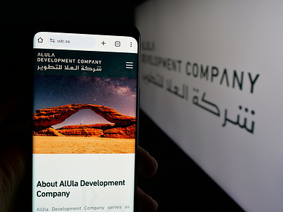 In this photo illustration, a smartphone with the web page of business Al-Ula Development Company (UDC) is seen on screen in front of logo.