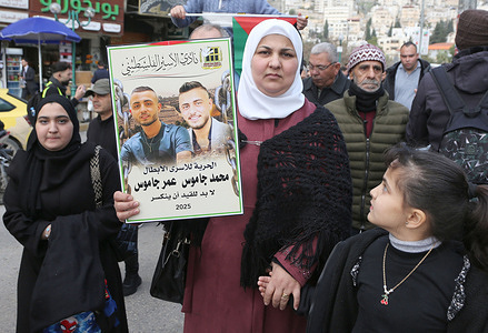 A Palestinian woman seen raising a picture of her family members that were imprisoned in Israeli jails . Palestinians blocked the streets during a protest against the freezing of their sons' salaries, demanding that the Palestinian Authority resume their payments.