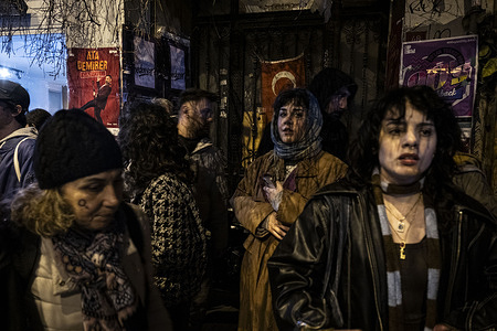 Two women stand on the sidewalk, watching participants in the feminist night march. Thousands of women gathered in Beyoğlu for the traditional Feminist Night March, organized in Istanbul as part of International Women's Day on March 8th.