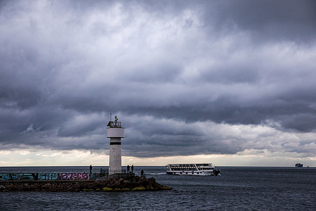 People are seen fishing at the Inciburnu Lighthouse on a cloudy day in Kadikoy district of Istanbul.