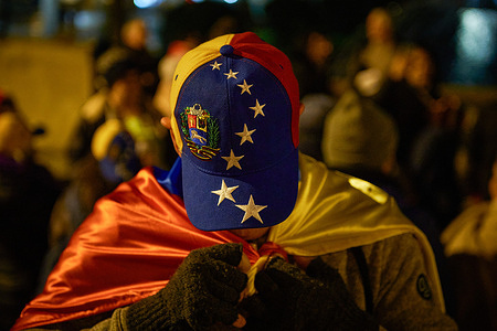 A participant with a Venezuelan cap wraps a flag of Venezuela during a demonstration to demand the appointment of Venezuelan President-elect Edmundo Gonzalez Urrutia.