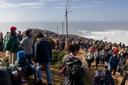 Spectators gather along the coastal path near the Tudor Nazaré Big Wave Challenge venue during the 2025/2026 WSL season. Thousands gathered on the cliffs of Nazaré, Portugal, to witness the Tudor Nazaré Big Wave Challenge, part of the 2025/2026 WSL season. Against a backdrop of roaring Atlantic swells, surfers were towed into colossal waves by jet skis, carving lines down walls of water that towered above the ocean. Spectators lined the headland and surrounding hills, capturing the spectacle with phones and cameras. The atmosphere was electric—equal parts awe, adrenaline, and celebration of human courage in the face of nature’s raw power.