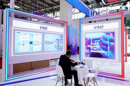 A man sits at a table in the Intel exhibition area of the 3rd China International Supply Chain Expo, with Intel - themed displays around.