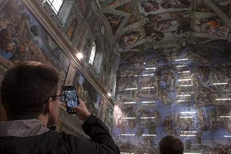 A tourist takes a photo during the press briefing on the maintenance of Michelangelo's Last Judgement in the Sistine Chapel.
