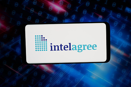 In this photo illustration, the logo of US AI CLM software company IntelAgree LLC is displayed on a smartphone in front of abstract background on computer screen.